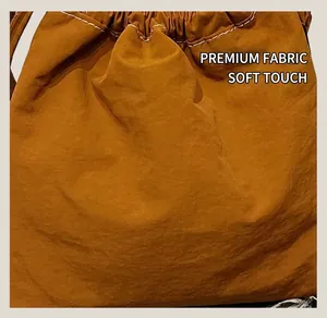 Detail of a brown drawstring crossbody bucket bag with contrasting white stitching details