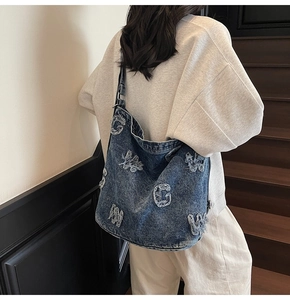 Detail of vintage denim tote bag featuring distressed letter patches and washed blue fabric