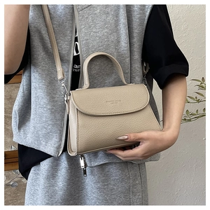 Détail du sac à main en cuir beige à motif litchi avec boucle en métal et poignée ronde