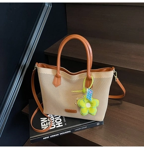 Détail du sac cabas en maille avec lanières en cuir et breloque tournesol en peluche