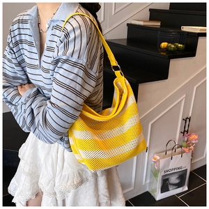 Detail of yellow and white striped knit tote bag with leather trim on model