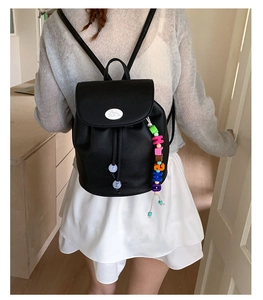 Detail of a black pebbled leather mini backpack with rabbit logo and colorful bead charm