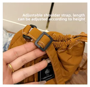 Detail showing the adjustable shoulder strap with black buckle on caramel nylon bucket bag