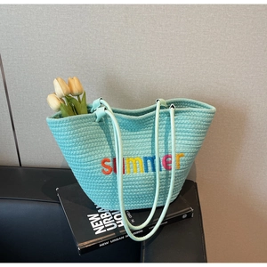 Close-up of mint green woven tote with summer embroidery and decorative tulips