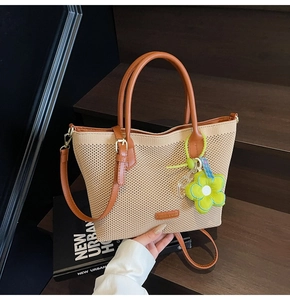 Détail du sac cabas en maille tressée avec anses en cuir marron et breloque fleur