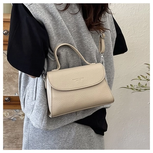 Détail du sac bandoulière en cuir beige avec texture grainée et bandoulière ajustable