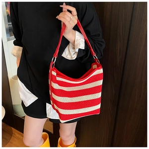 Detail of red and white striped woven tote with leather shoulder strap and metal rings