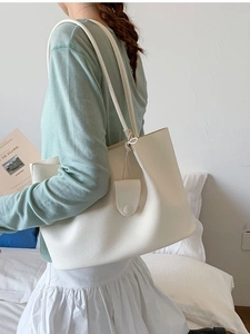 Minimalistische cremefarbene große Tote-Tasche mit Lederstruktur am Modell