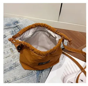 Brown nylon drawstring bucket bag detail showing internal zipper pocket and stitching