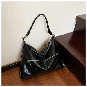 Detailed macro view of black glossy hobo bag featuring silver metal zipper and wrinkled texture