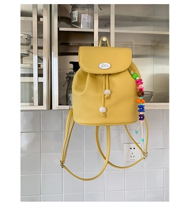 Detail view of yellow lychee leather backpack with bunny logo and colorful letter beads