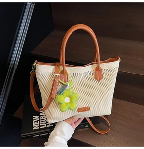 Détail du sac cabas en maille tressée avec poignées en cuir et breloque fleur verte