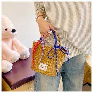Detail of woven straw bag featuring colorful knot accents and white drawstring liner
