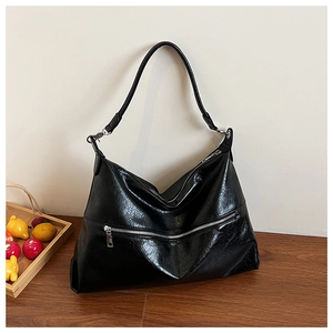 Detail shot of the large black tote bag featuring oil wax leather texture and silver zipper