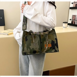 Detail showing high-capacity camouflage tote bag with orange leather logo and wide strap