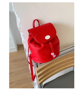Detail of red pebbled leather backpack with a white rabbit logo and drawstring closure
