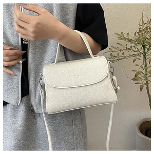 Détail de la texture en cuir litchi blanc sur un sac à main avec marquage FASHION & BAGS