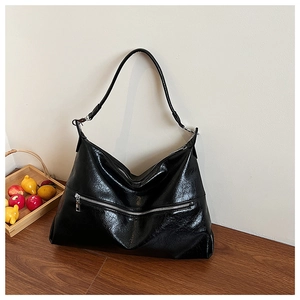 Detail of glossy black oil wax leather texture and horizontal zipper on tote bag