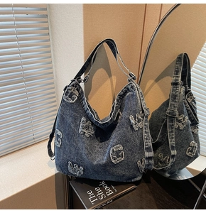 Detailed close-up of distressed denim tote with frayed letter patches and vintage wash