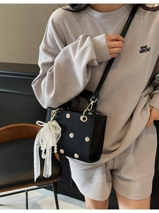 Black crossbody bag with daisy embroidery and pearl lace bow charm on model
