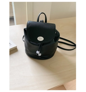 Detail of black lychee texture leather backpack with a white rabbit buckle and drawstring