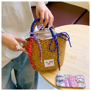Detail of hand-woven straw tote with colorful braided rope handles and drawstring liner