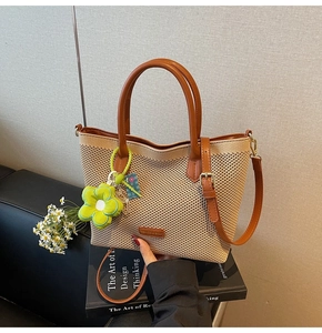 Détail du sac fourre-tout tissé avec poignées en cuir marron et breloque tournesol vert
