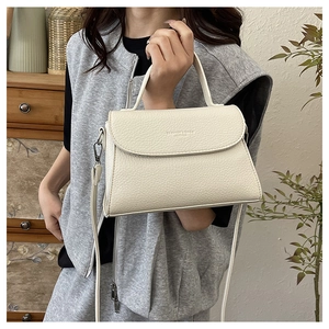 Détail d'un sac à main en cuir grainé blanc cassé avec ferrures argentées et logo embossé