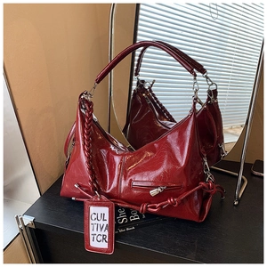 Detailed close-up of a glossy burgundy tote bag with braided handle and side logo tag