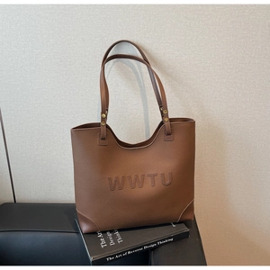Close-up of caramel brown tote bag featuring WWTU embossed letters and gold rivets