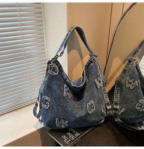 Detailed macro view of denim tote bag featuring frayed G and W patchwork on washed blue fabric