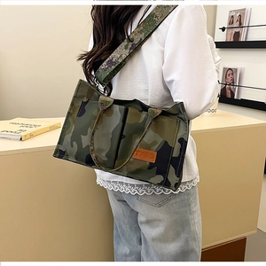 Detail view of camouflage tote bag with wide adjustable strap and brand leather patch