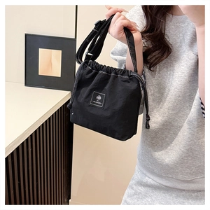 Detail of black nylon drawstring crossbody bag featuring contrast white stitching and strap