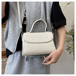 Détail d'un sac à bandoulière beige avec texture grainée et poignée supérieure arrondie
