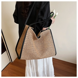 Detail of woven straw tote bag with black leather handles and trim for beach holidays