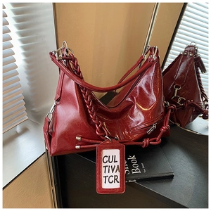 Detail of burgundy waxed leather hobo bag with woven strap and metallic charms