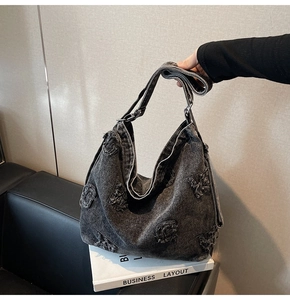 Close-up of deep gray denim tote bag featuring frayed G-letter patch and adjustable strap