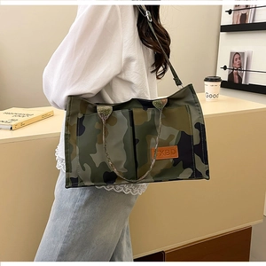 Detail of camouflaged tote bag with leather logo patch and adjustable shoulder strap