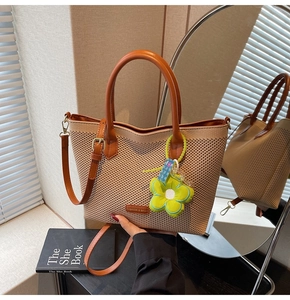 Détail du sac cabas tissé avec poignées en cuir marron et charm tournesol vert peluche