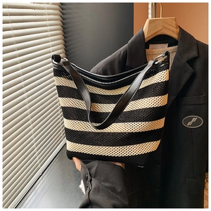 Detail of black and white striped woven bag with leather strap and silver metal rings