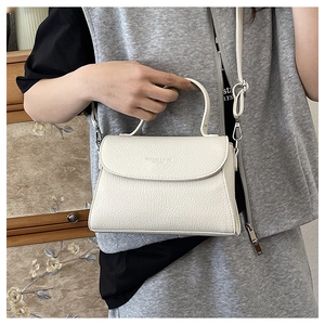 Détail du sac à bandoulière blanc crème avec texture en cuir grainé et poignée