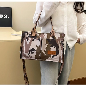 Detail shot of the camouflage tote bag showing dual front pockets and TXBD brand label