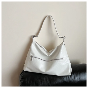Detail of white tote bag showing glossy faux leather texture and metallic zipper pocket