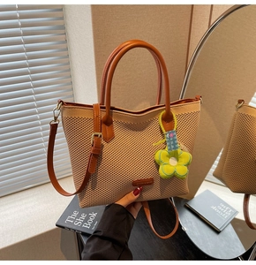 Gros plan du sac cabas tissé avec poignée en cuir marron et breloque fleur verte