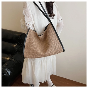 Close-up of woven straw tote bag with herringbone texture and black leather straps