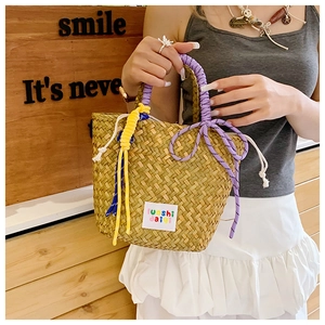 Close-up of handmade woven straw bag featuring purple and yellow braided rope handles