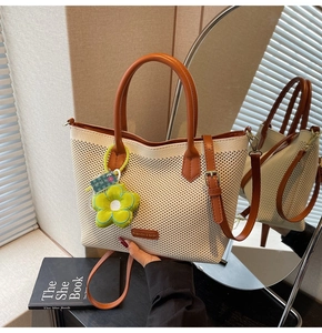 Détail d'un cabas tissé beige avec anses en cuir marron et charme floral vert