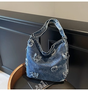 Close-up of blue denim hobo bag featuring vintage letter patches and raw edge details