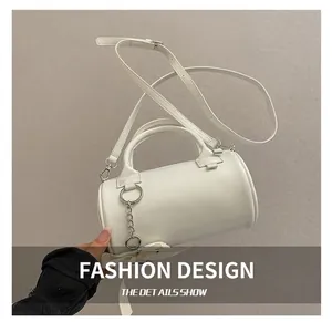 Detail of white cylindrical Boston bag featuring smooth leather texture and silver chain link
