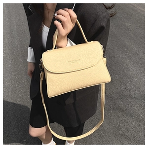 Gros plan d'un sac à main beige en cuir grainé avec bandoulière réglable chic